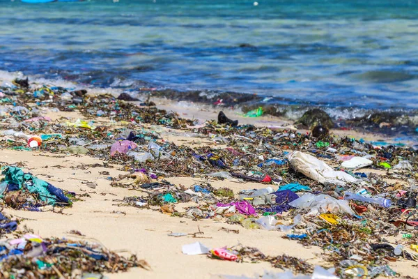 Closeup plastic trash on the sandy beach of a tropical sea. Ecological problem of garbage in the oceans