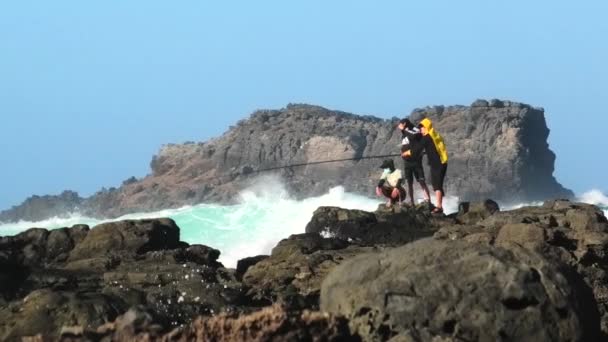 医疗上蒙面的渔民在流行病期间从岩石上捕鱼 — 图库视频影像
