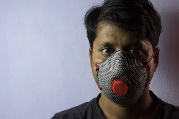 an Indian man wearing safety nose mask looking at camera white background corona virus or covid-19 protection