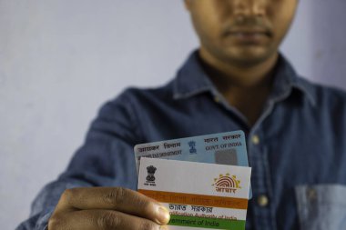 Beyaz arka planda PAN ve aadhaar kartları tutan Hintli bir adam seçici odaklı ya da sığ alan derinliğinde