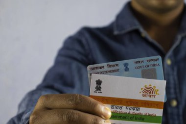 Beyaz arka planda PAN ve aadhaar kartları tutan Hintli bir adam seçici odaklı ya da sığ alan derinliğinde