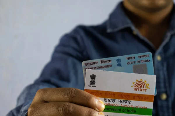 Beyaz arka planda PAN ve aadhaar kartları tutan Hintli bir adam seçici odaklı ya da sığ alan derinliğinde