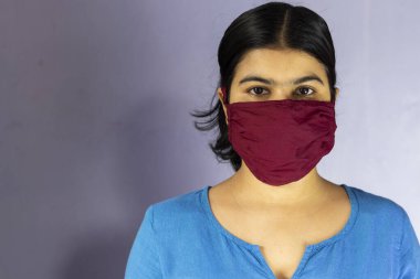 Ev yapımı pamuk burun maskesi takan ve Corona virüsü veya Cvid-19 korunması için kameraya bakan Hintli bir kadının vesikalık fotoğrafı.