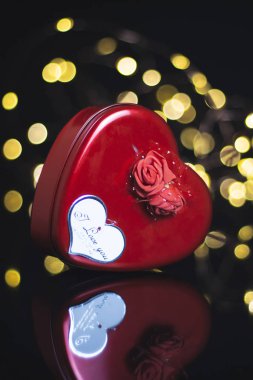 Sevgililer Günü geçmişi. Hediyeler, kırmızı gül, konfeti, siyah arka planda kalp şeklinde bokeh ışıkları olan zarf. Sevgililer Günü konsepti. Düz konum, ön görünüm, seçici odak, kopyalama alanı