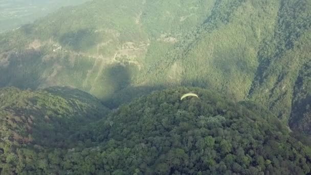 ジャラバコア ドミニカ共和国の美しい緑の山の風景の上を飛ぶ黄色のパラグライダーの上から撮影されたドローン — ストック動画