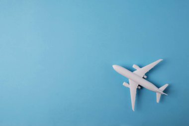 Metin, hava taşımacılığı, turizm ve seyahat için mavi arka planda beyaz renkli oyuncak bir uçak modeli.