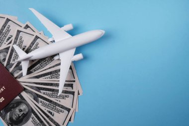Mavi arka planda beyaz oyuncak uçak modeli, Amerikan doları ve pasaportu, metin, uçak bileti konsepti, hava taşımacılığı maliyeti eklenecek yer.