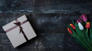 Renkli laleler buketi ve eski ahşap arka planda fotokopi alanı olan hediye kutusu