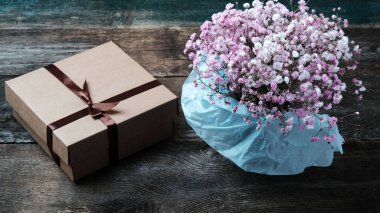 Hediye karton kutu ve eski bir ahşap zemin üzerinde bir buket çiçek fotokopi alanı ile.