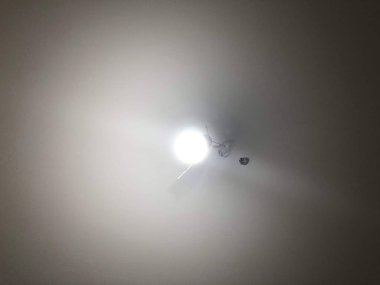 Homeliness, a light on the mirror, a handle on the cabinet, a plug in the socket, black cord, iron handle, the light is on, there is no chandelier, white ceiling, bright interior. A handle with a lock, a wooden door, a torn sofa, a white sofa.