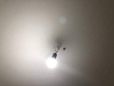 Homeliness, a light on the mirror, a handle on the cabinet, a plug in the socket, black cord, iron handle, the light is on, there is no chandelier, white ceiling, bright interior. A handle with a lock, a wooden door, a torn sofa, a white sofa.