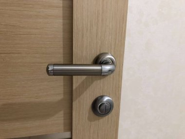 Homeliness, a light on the mirror, a handle on the cabinet, a plug in the socket, black cord, iron handle, the light is on, there is no chandelier, white ceiling, bright interior. A handle with a lock, a wooden door, a torn sofa, a white sofa.
