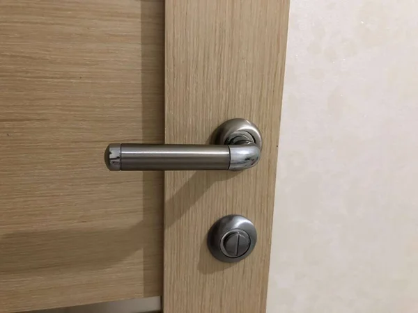 Homeliness, a light on the mirror, a handle on the cabinet, a plug in the socket, black cord, iron handle, the light is on, there is no chandelier, white ceiling, bright interior. A handle with a lock, a wooden door, a torn sofa, a white sofa.
