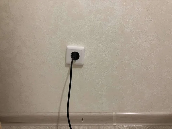 Homeliness, a light on the mirror, a handle on the cabinet, a plug in the socket, black cord, iron handle, the light is on, there is no chandelier, white ceiling, bright interior. A handle with a lock, a wooden door, a torn sofa, a white sofa.