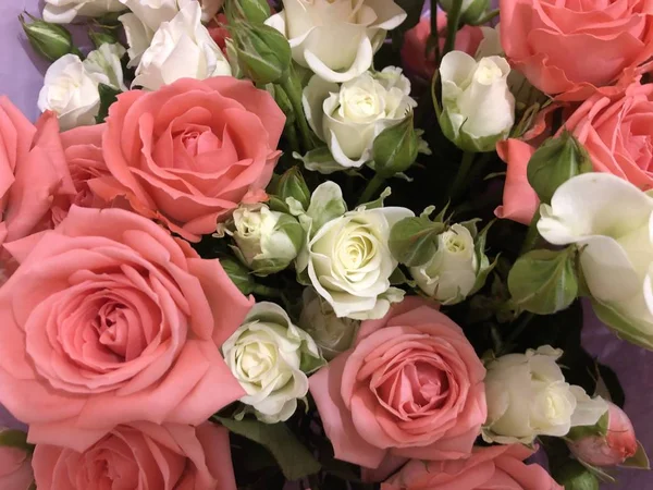 Bouquet of roses.  Pink and white flowers.  Spring bouquet.  Gift to your girlfriend.  Set of flowers for a woman.  Green stems with leaves.  Fresh flowers in paper and a vase.  Plants at home.  White and bright room.  Lovers day.  Happy Valentine\'s