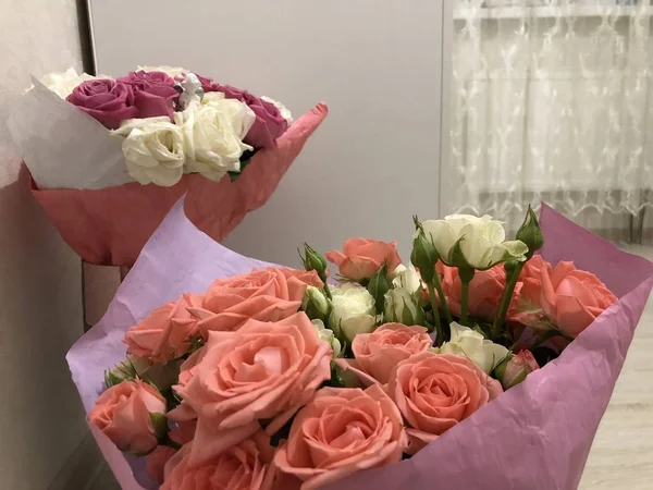 一束玫瑰 粉红色和白色的花 春天的花束送给你女朋友的一束花给一个女人绿色的茎上有叶子 纸上的鲜花和花瓶 家里的植物 白色明亮的房间 情人的日子 情人节快乐 — 图库照片