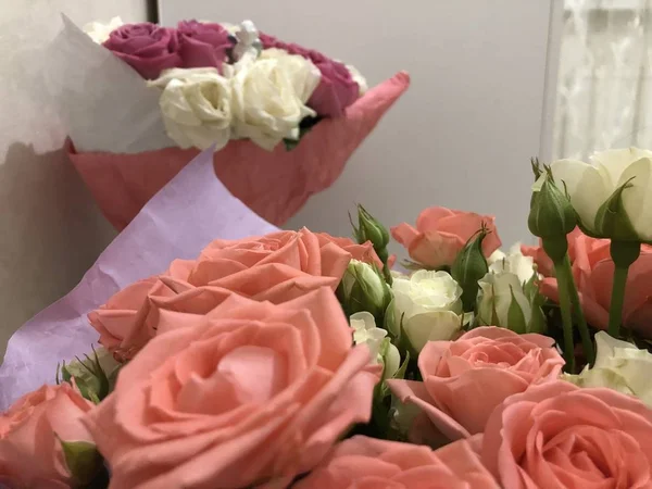Bir buket gül. Pembe ve beyaz çiçekler. Bahar buketi. Kız arkadaşına hediye et. Bir kadın için çiçek seti. Yapraklı yeşil saplar. Kağıt üzerinde taze çiçekler ve bir vazo. Evdeki bitkiler. Beyaz ve parlak bir oda. Aşıklar günü. Sevgililer Günün kutlu olsun