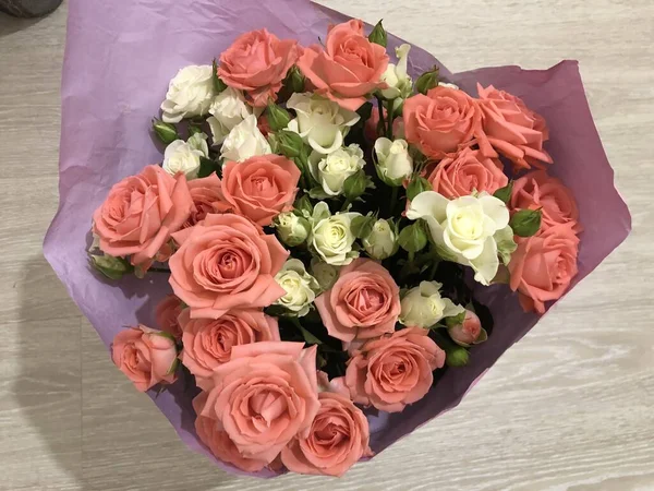 Bouquet of roses.  Pink and white flowers.  Spring bouquet.  Gift to your girlfriend.  Set of flowers for a woman.  Green stems with leaves.  Fresh flowers in paper and a vase.  Plants at home.  White and bright room.  Lovers day.  Happy Valentine\'s