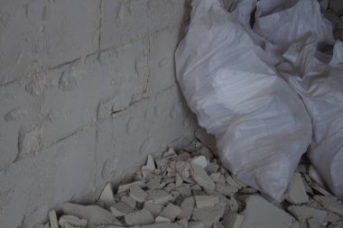 Yığınla inşaat enkazı içinde beyaz inşaat çantaları. Kirlilik konsepti. Çöp sahasındaki bir çöp yığını. Yasadışı çöp sahası