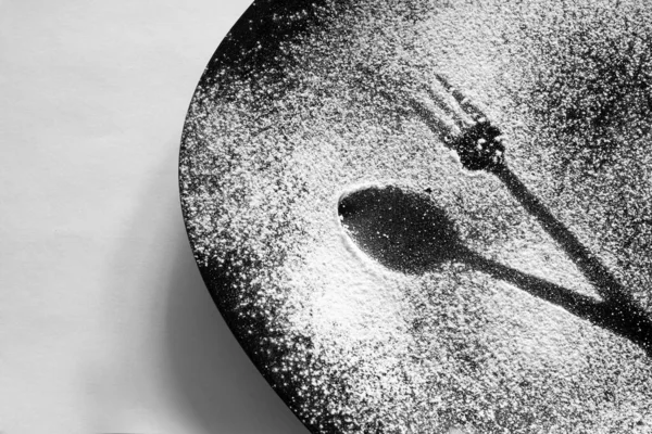 drawing of a spoon and fork with flour on a black plate