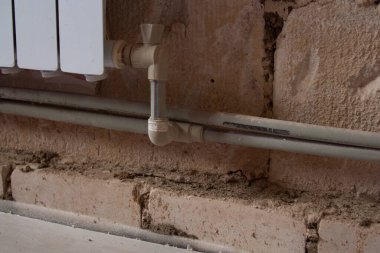 Odadaki tuğla duvarda ısıtıcı var. Isıtma boruları