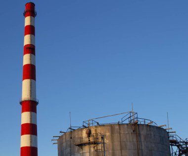 Yakıt tankları ve bacalar mavi gökyüzüne karşı.