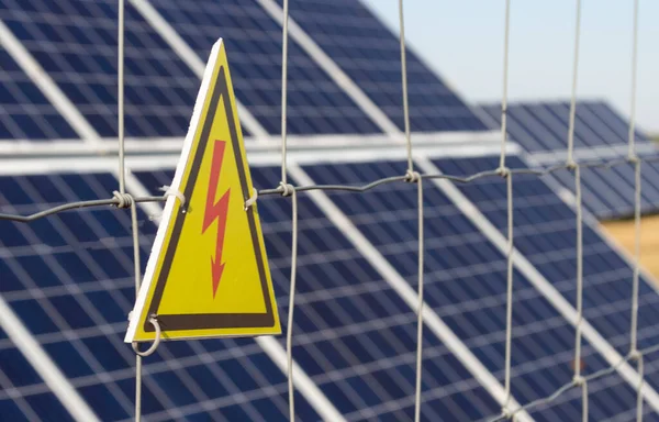 Güneşle yenilenebilir güneş enerjisi kullanan bir enerji santrali. Güneş panelleri dışarıda dikenli tellerin arkasında duruyor. Bu da elektrik şoku tehlikesinin işareti..