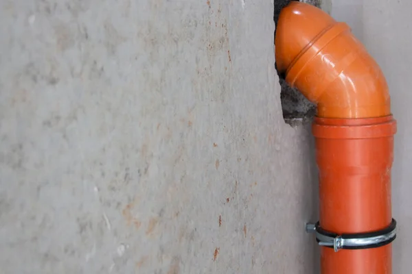 El tubo de alcantarillado rojo o tubería de alcantarillado en la pared de hormigón se fija con sujetadores hechos de hamut.copyspace para el texto . — Foto de Stock