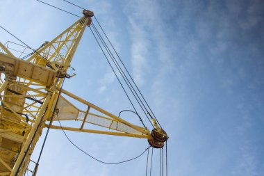 Bir inşaat alanında vinç inşaatı. Mavi gökyüzünün ve parlak güneşin arka planında.