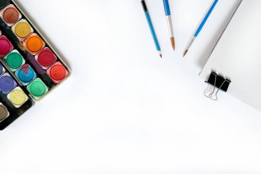 Suluboya boya kutusu ve beyaz arka planda fırçalar. Düz yatış, üst görünüm