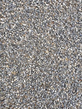 Tam kare olarak gri ve kahverengimsi renklerde çakıl taşlarıyla kaplı bir kaldırımın yakın görüntüsü.