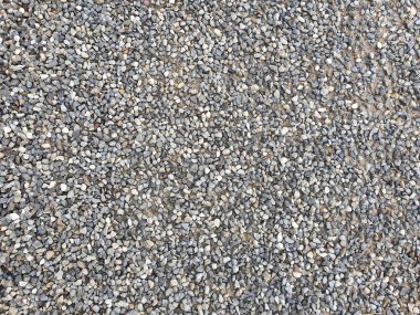 Tam kare olarak gri ve kahverengimsi renklerde çakıl taşlarıyla kaplı bir kaldırımın yakın görüntüsü.