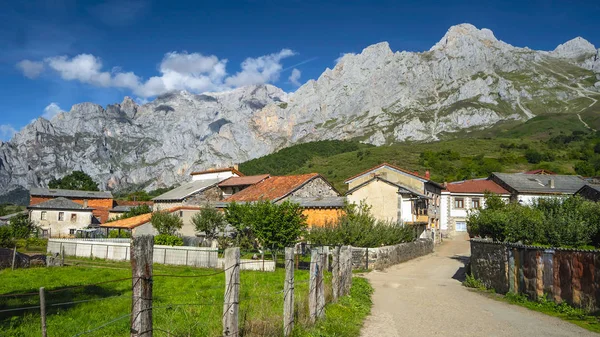 Summer landscape of a mountain village in the national park Picos de Europa. Rocky mountains, green meadow, village.