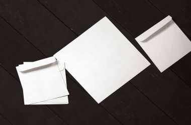 Siyah arka planda beyaz zarf ve kartpostal. Üst görünüm boş zarf modeli ve boş antet sunum şablonu. Tasarımınız için boş sayfa.