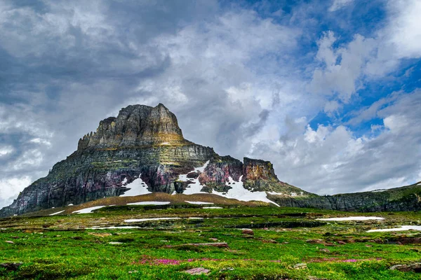 4820_A break in the storm clouds highlights the Clements Mountain meadow of wildflowers at Glacier National Park, Montana