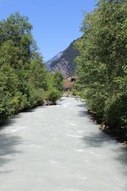 İsviçre 'deki Lauterbrunnen Vadisi' nin dağlık arazisinden akan gri / beyaz renkli tipik bir buzul nehri..