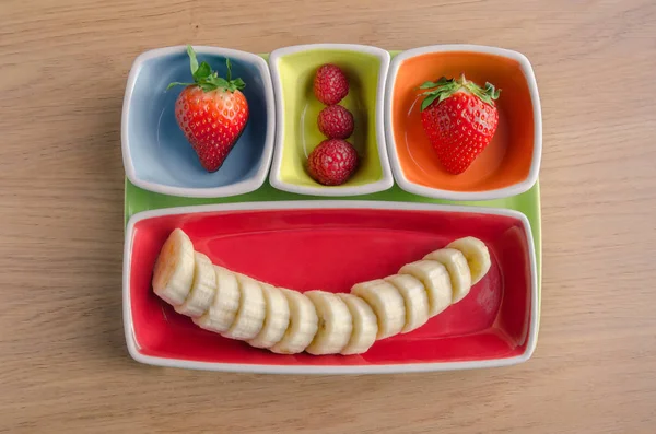 Набір фруктів на барвистій тарілці у вигляді щасливого обличчя — стокове фото