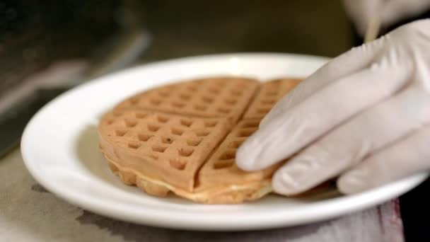 Männliche Hand im Handschuh legt die Waffeln auf einen Teller — Stockvideo