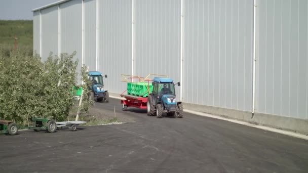 Dva traktory kombinují transportní jablka v zelených krabicích — Stock video