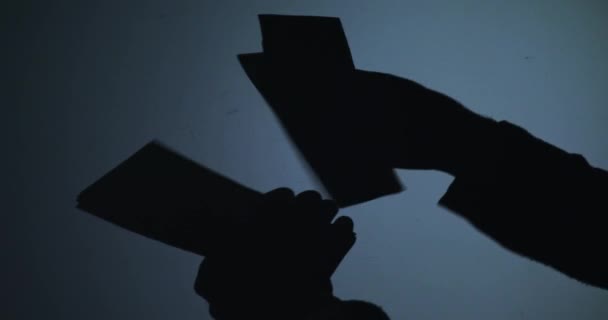 Black silhouette of hands counting banknotes on blue background — Stock Video