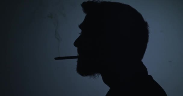 Silhouette mand ryge cigaret på en blå baggrund – Stock-video