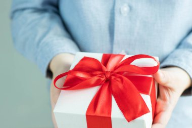 Çocuklar hediye kutusunu tutuyorlar. Siyah kurdeleli beyaz hediye kutusu. Üst görünüm