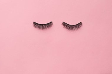 Pembe arka planda sahte kirpikler. Makyaj malzemesi. Üst görünüm