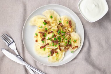 Kızarmış soğan ve pastırmalı ev yapımı hamur tatlısı. Geleneksel olarak, Ukrayna yemeği yeşil soğanlarla süslenir. Tabakta hamur köftesi var.
