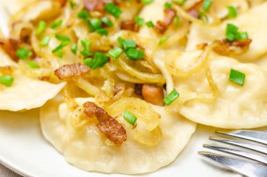 Kızarmış soğan ve pastırmalı ev yapımı hamur tatlısı. Geleneksel olarak, Ukrayna yemeği yeşil soğanlarla süslenir. Tabakta hamur köftesi var.