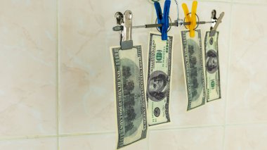 Çiğ dolarlar elbise rafında asılı.