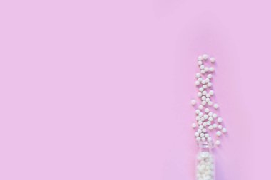 Pembe arka planda homeopatik globullar ve cam şişe. Alternatif Homeopati