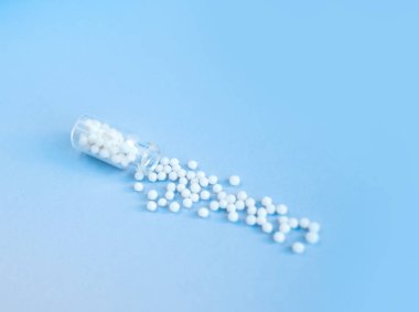 Pembe arka planda homeopatik globullar ve cam şişe. Alternatif Homeopati