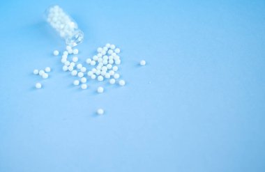 Pembe arka planda homeopatik globullar ve cam şişe. Alternatif Homeopati
