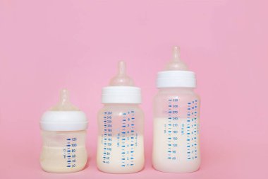 Pembe arka planda bir bebek için bir şişe süt..